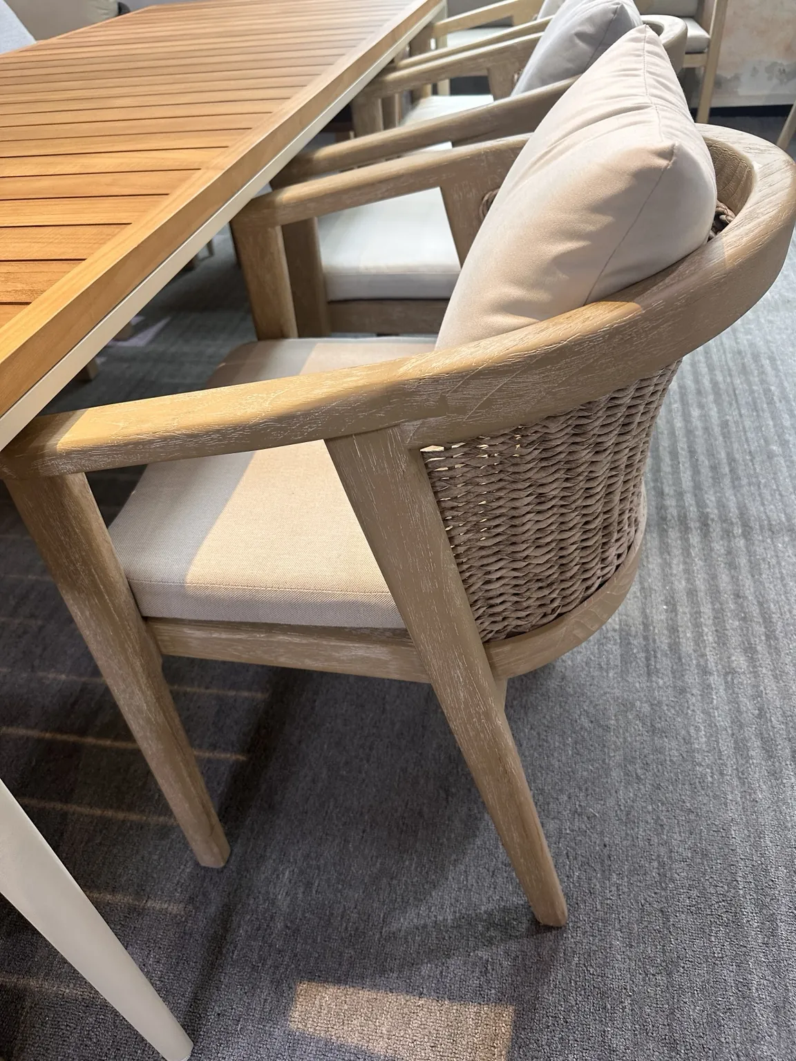Whitewashed wood and woven dining chair beside a plank table